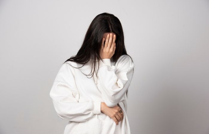 Young adult sitting in a parked car outside a clinic, head lowered, hesitating before going in for STI testing.